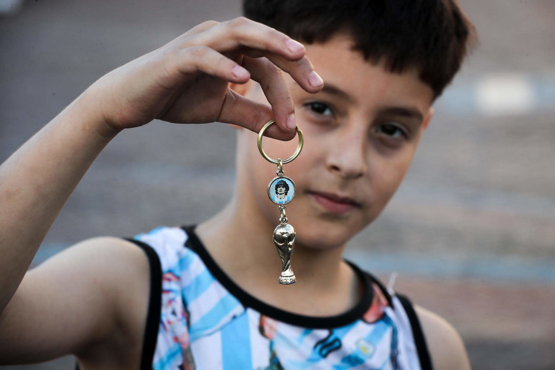 Un niño fue registrado este domingo, 18 de diciembre, al mostrar un llavero con el trofeo de la Copa del Mundo y el retrato de Diego Maradona, durante un banderazo de los aficionados, en Buenos Aires (Argentina). EFE/Raúl Martínez